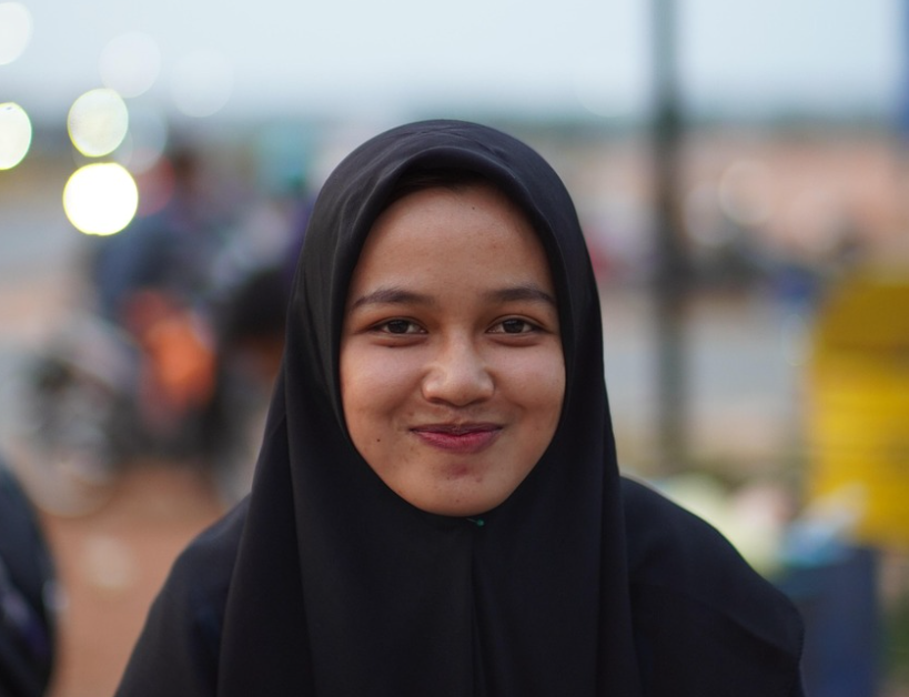Warm smiling Indonesian woman in black hijab - authentic everyday beauty