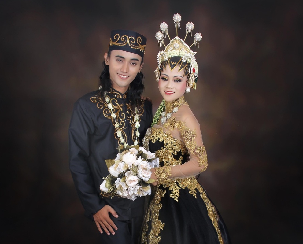 Traditional Indonesian Javanese wedding couple in ceremonial black and gold attire